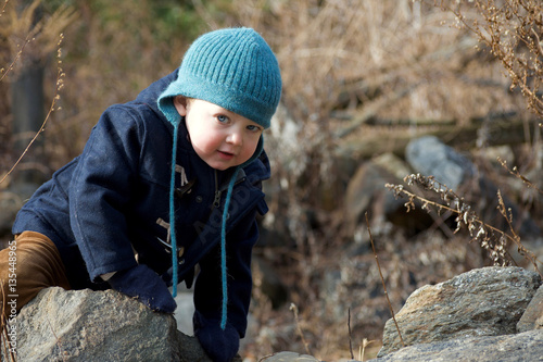 adorable toddler boy climbing rock during wintertime
