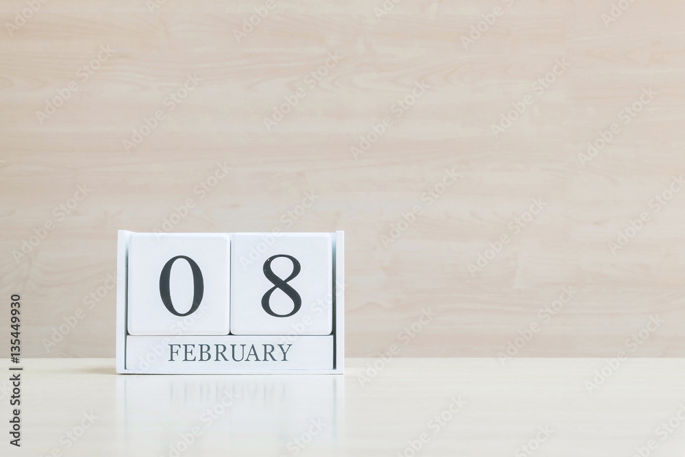 Closeup surface white wooden calendar with black 8 february word on blurred brown wood desk and wood wall textured background with copy space in selective focus at the calendar Closeup surface white wooden calendar with black 8 february word on blurred brown wood desk and wood wall textured background with copy space in selective focus at the calendar
