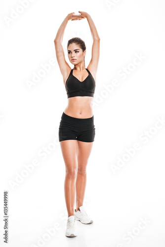 Full length of graceful woman athlete standing and stretching hands