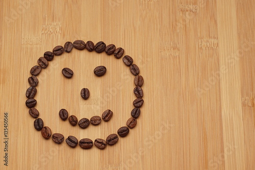 A smile face made from coffee beans on a bamboo background