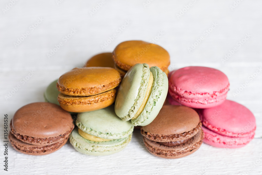 Obraz premium Colorful macarons, macaroons cake on white wooden background closeup 
