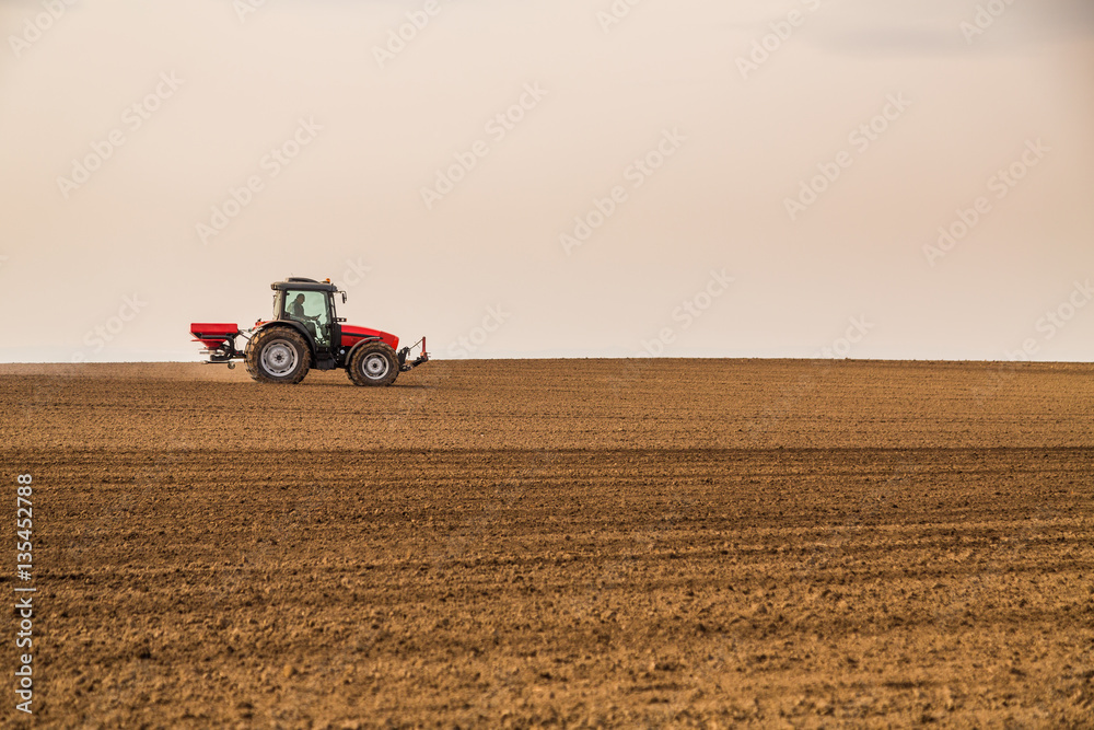 Obraz premium Farmer fertilizing arable land with nitrogen, phosphorus, potassium fertilizer