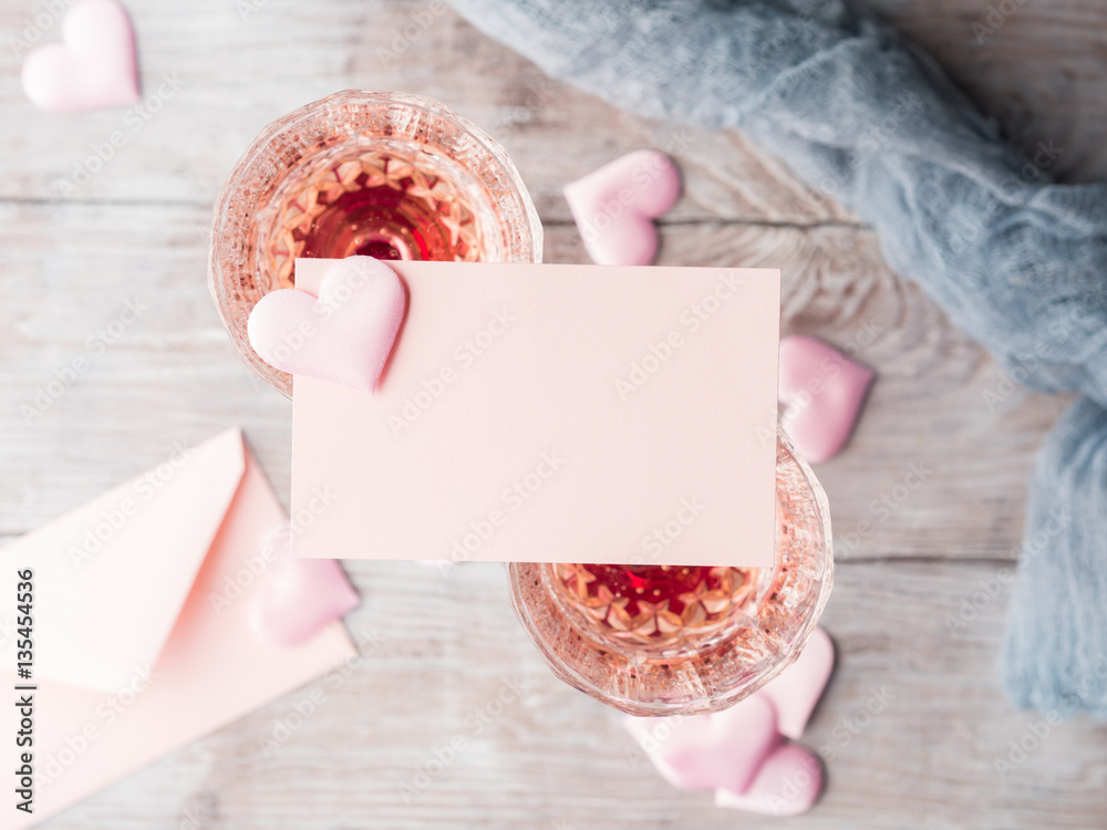 Φωτογραφία Two stemmed champagne glasses with pink hearts blank paper note card to fill with your text on wooden textured background