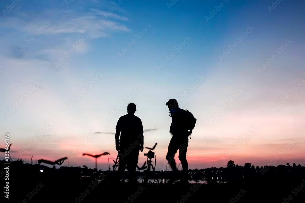 Silhouette photographers with sunset background