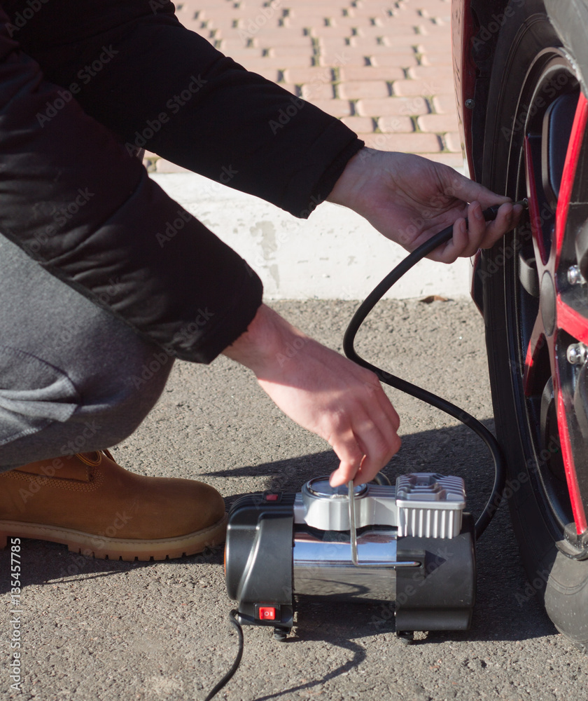 Obraz premium Man checking air pressure and filling air in the tires of car