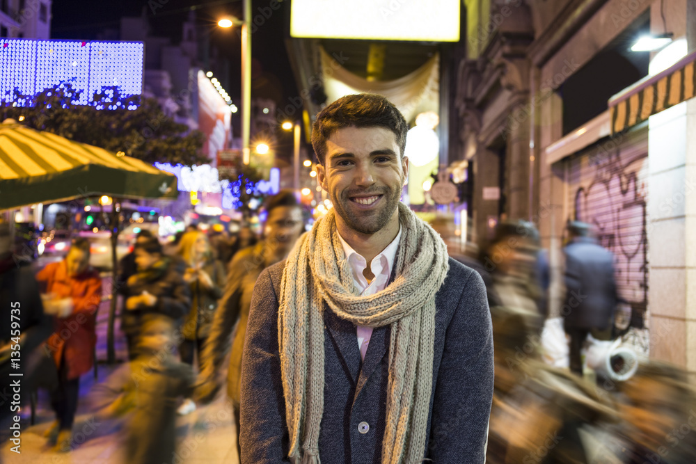 Portrait of smiling man in the city with unfocused people at night Portrait of smiling man in the city with unfocused people at night