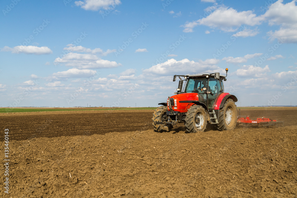 Farmer in tractor preparing land with seedbed cultivator as part of pre seeding activities in early spring season of agricultural works at farmlands. Farmer in tractor preparing land with seedbed cultivator as part of pre seeding activities in early spring season of agricultural works at farmlands.