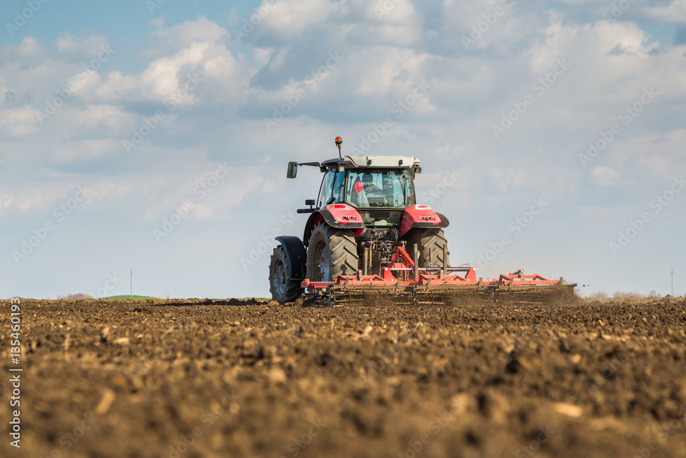 Farmer in tractor preparing land with seedbed cultivator as part of pre seeding activities in early spring season of agricultural works at farmlands. Farmer in tractor preparing land with seedbed cultivator as part of pre seeding activities in early spring season of agricultural works at farmlands.