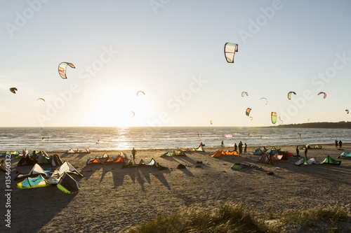 Kiteboarders on beach against clear sky