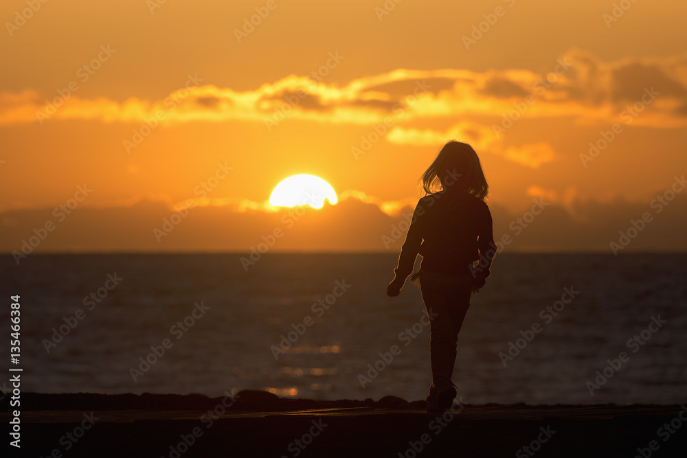 Child on sunset beach during beautiful sunset
