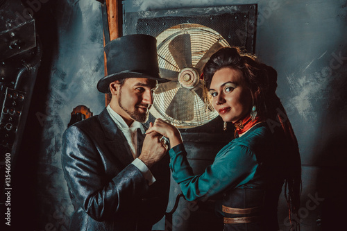 Pretty flirting couple dressed in vintage costumes on the dark room background.