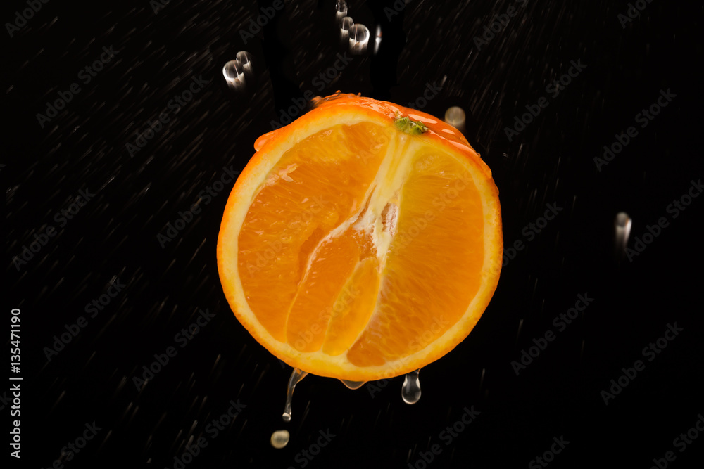 half an orange with drops isolated on a dark background