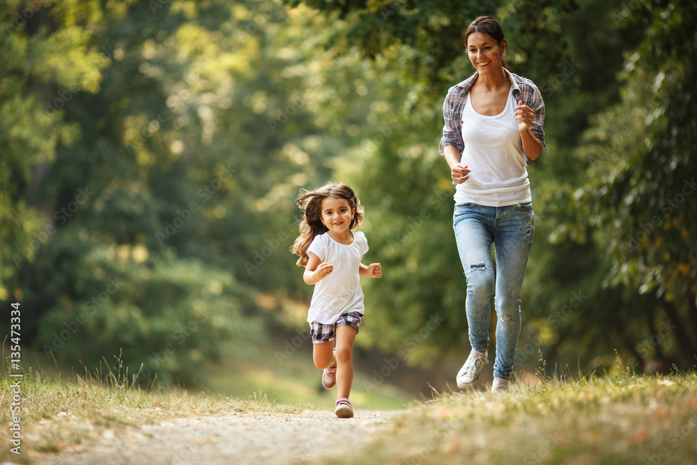 Mother and daughter playing and running around the park on beautiful morning. Mother and daughter playing and running around the park on beautiful morning.