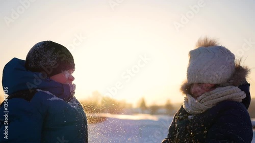 cheerful children playing in the snow throwing snow up in park