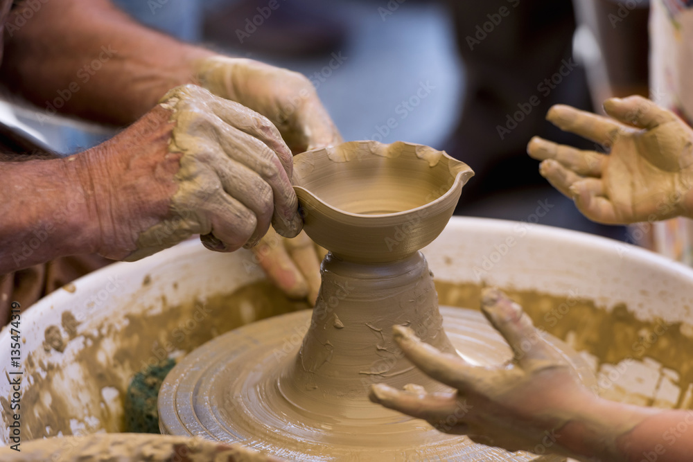Close-up of a potter's wheel, teaching a child to make a clay object