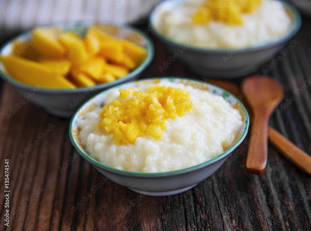 Rice pudding with mango jam in bowls with wooden spoons
