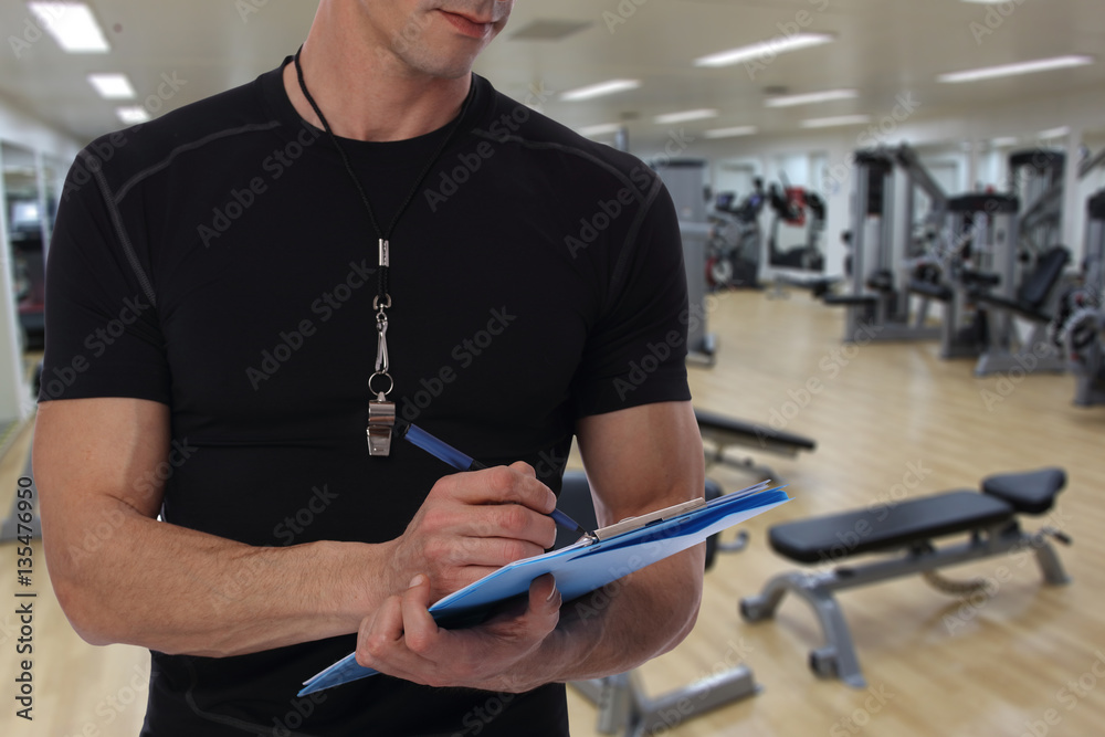 Personal fitness trainer with workout plan close up in gym background. Sport, fitness and healthy life style concept.