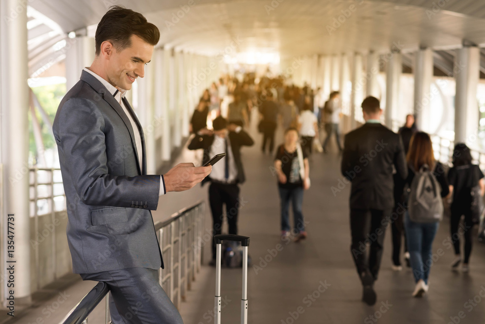 Business man traveling use smart phone on the walk way with crow Business man traveling use smart phone on the walk way with crow