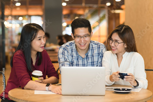 3 teenagers friends meet in coffee shop, using technology device