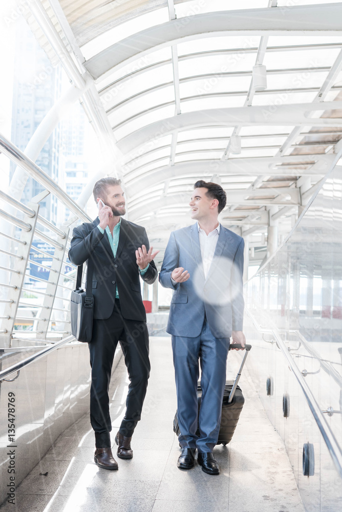 Two Westerner Business men talk and use smart phone on the publi Two Westerner Business men talk and use smart phone on the publi