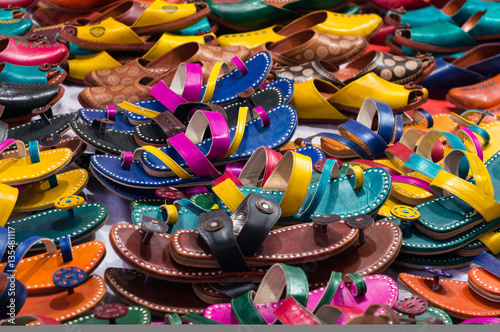 Pile of colorful handmade leather slippers spread out on a sidewalk for selling