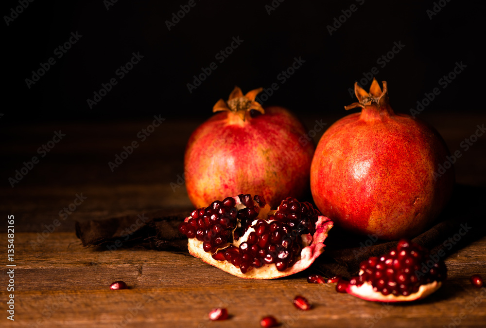 Pomegranate fruits with grains on wooden table. Dark moody. Life style. Pomegranate fruits with grains on wooden table. Dark moody. Life style.