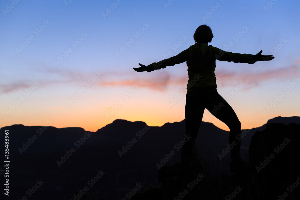 Woman climbing success silhouette in mountains sunset