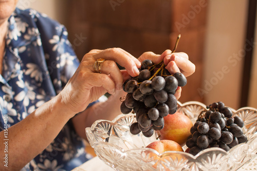 Close up of old woman's hands holding bunch of grapes.
