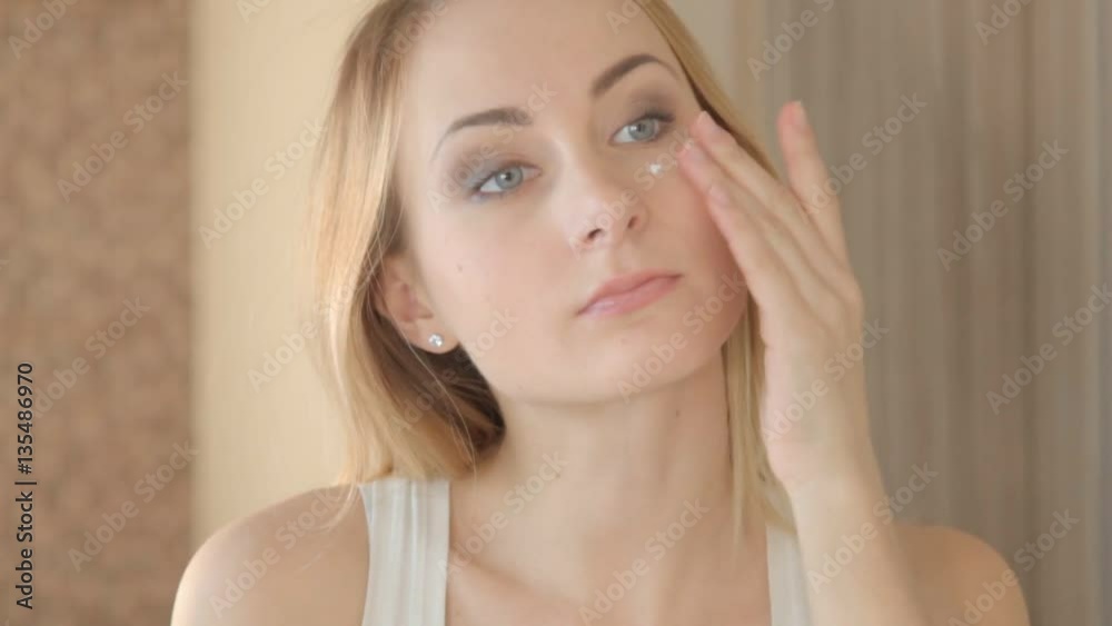 Beautiful model putting face cream in bathroom. Beautiful model putting face cream in bathroom.