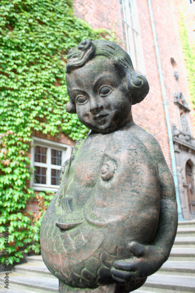 Little girl and fish statue in ancient building in Stockholm used as city hall
