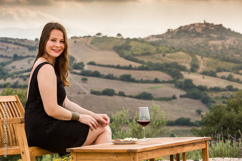 Girl with a glas of wine at sunset in Tuscany, Italy