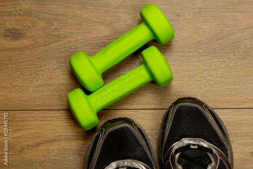 fitness lifestyles concept, dumbbells, sport shoes on wood background top view