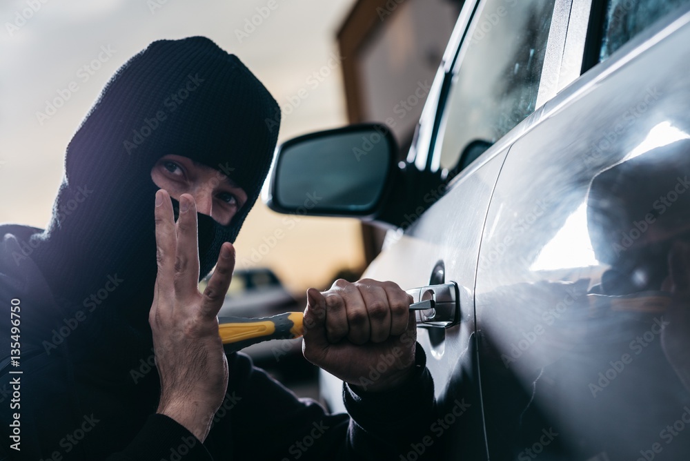 Auto thief in black balaclava trying to break into car Auto thief in black balaclava trying to break into car