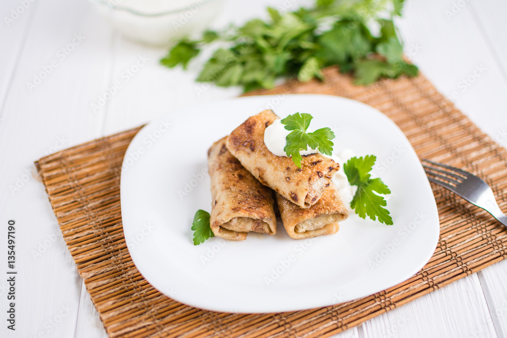 Pancakes filled with meat stuffing on a white plate