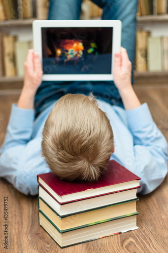 Teenager working on the tablet. Books in the background.