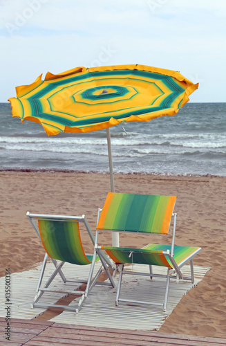 rough sea and the beach with an umbrella in the wind with two de photo