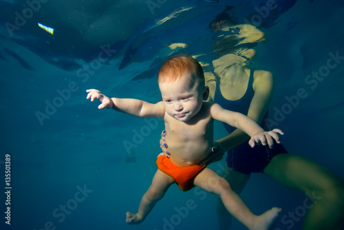 Mother holding baby under water and teaches him to swim. Portrait. Close-up. Shooting underwater. Landscape orientation