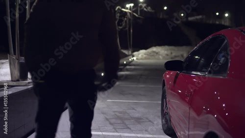 Wallpaper Mural Young man gets out of a red car at night at the parking and closes the door. Back view. Torontodigital.ca