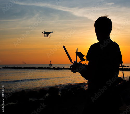 Man operating of flying drone quadrocopter at sunset © Glebstock
