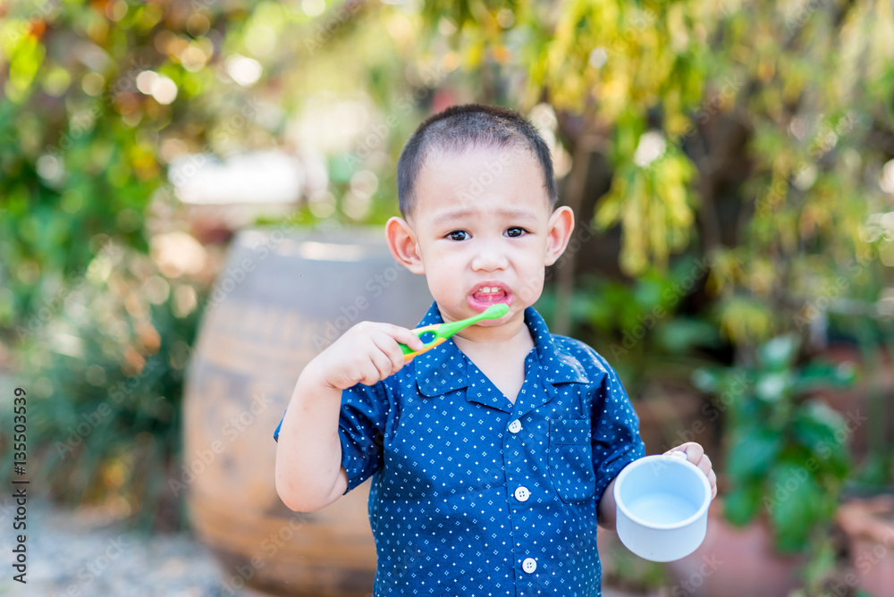 Thai baby boy brushing teeth. In baby hand holding cup