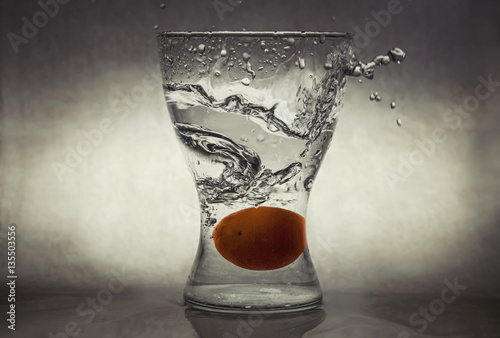 Satsuma dropped from height into a glass vase causing splash