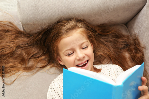 Small girl reading book on ...