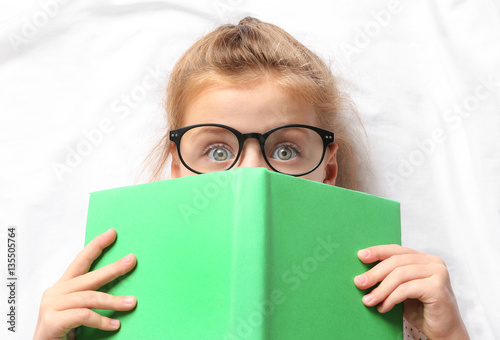 Cute girl with book lying o...