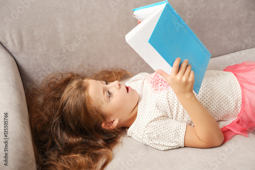 Small girl reading book on ...