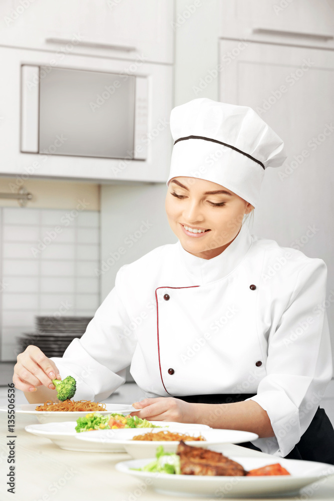 Young woman chef with different dishes on plates in modern kitchen Young woman chef with different dishes on plates in modern kitchen