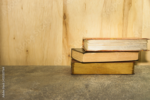 Vintage books on stone table against wooden background