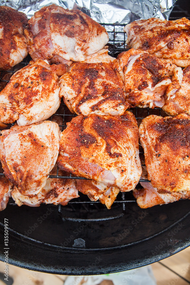 Seasoned grilled chicken cooking on barbecue in summer