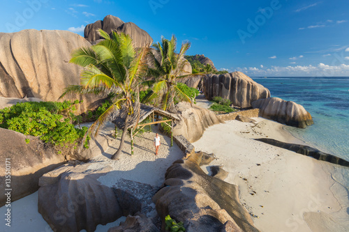 Female traveler emjoying amazing view of beautifully shaped granite boulders at picture perfect tropical Anse Source d'Argent beach, La Digue island, Seychelles. photo