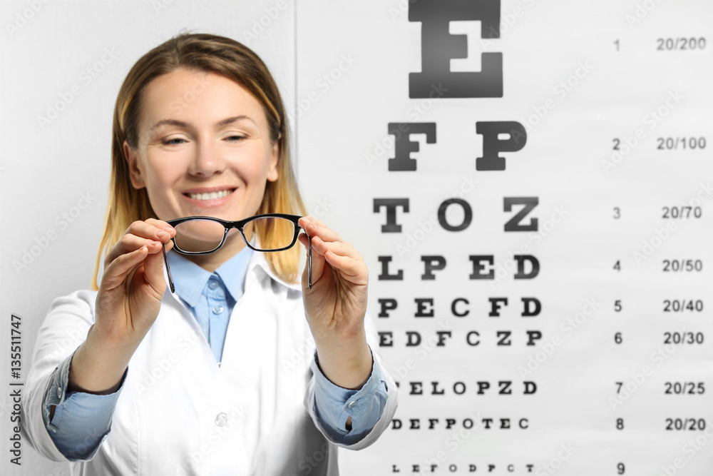 Young woman with spectacles on eyesight test chart background Young woman with spectacles on eyesight test chart background