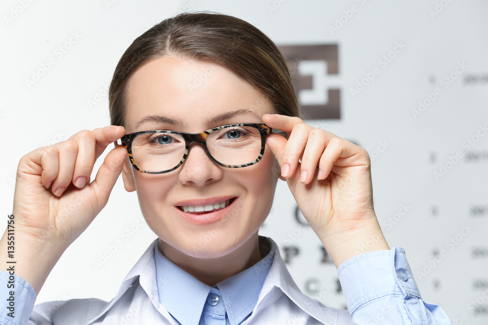 Young woman with spectacles on eyesight test chart background Young woman with spectacles on eyesight test chart background